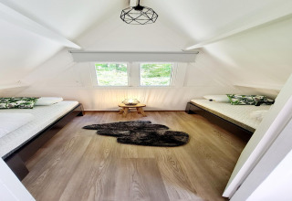 Helles Schlafzimmer im Chalet no 186 in Belgien mit zwei Einzelbetten, Fenstern und Holzdekor.