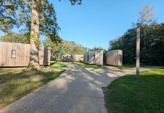 Piccole case in legno moderne a The Lodge by YourNature, Belgio, circondate da alberi e cielo sereno.