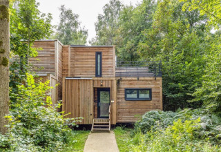 Modernes Holzhaus von The Cottage bei YourNature, gelegen im Wald und umgeben von grüner Natur.