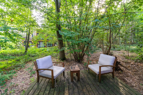 Buitenzitje met twee stoelen en een tafeltje op houten vlonder in het bos bij The Cottage, YourNature.