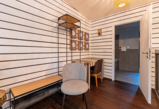 Innenaufnahme eines Glamping Cottage-Zimmers mit moderner Einrichtung, Holzmöbeln und Badezimmer.