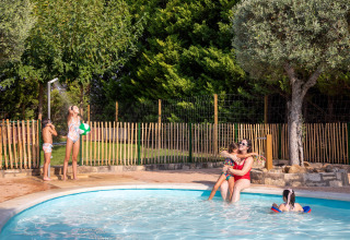 Niños y una adulta disfrutan de un día soleado en la piscina del parque vacacional TAIGA Lake Caspe, Aragón, España.