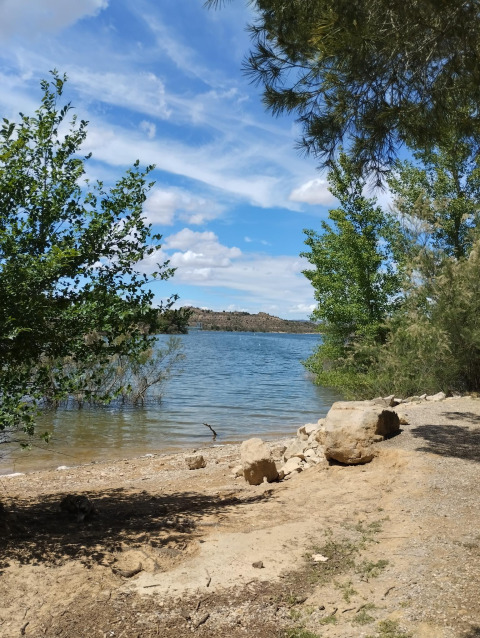 Vue sur le lac au parc de vacances TAIGA Lake Caspe en Aragón, Espagne, avec arbres et ciel bleu.