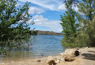Vue sur le lac au parc de vacances TAIGA Lake Caspe en Aragón, Espagne, avec arbres et ciel bleu.