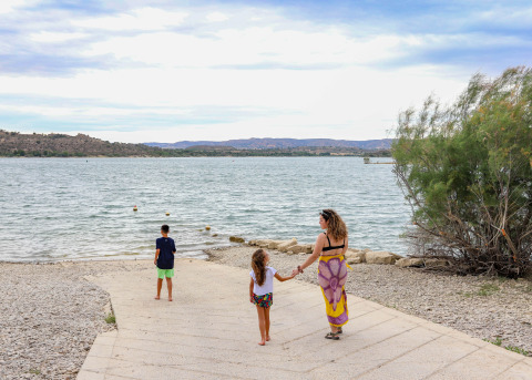 A woman and two children walk towards the water at TAIGA Lake Caspe holiday park in Aragón, Spain.