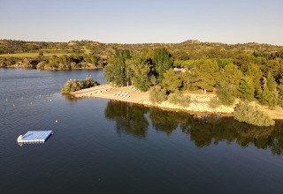 Vista aérea de la playa y embarcadero flotante en TAIGA Lake Caspe, rodeado de árboles en Aragón, España.