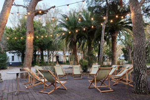 Outdoor lounge area with deck chairs and string lights at TAIGA Lake Caspe holiday park in Aragón, Spain.