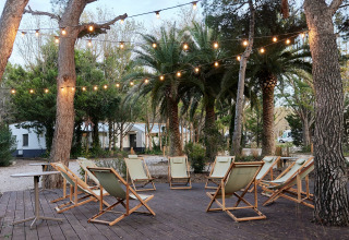 Outdoor lounge area with deck chairs and string lights at TAIGA Lake Caspe holiday park in Aragón, Spain.