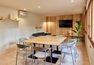 Bright meeting room at TAIGA Lake Caspe with modern chairs, wooden table, plant, sofa and TV.