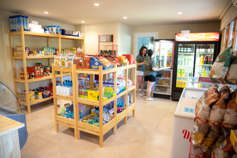 Two women shopping at a small grocery store in TAIGA Lake Caspe holiday park, Aragón, Spain.