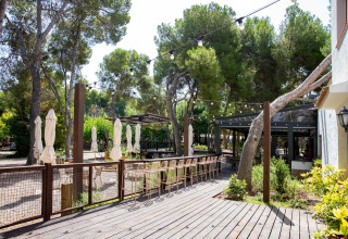 Sunny outdoor terrace with bar stools and string lights at TAIGA Lake Caspe holiday park in Aragón, Spain.