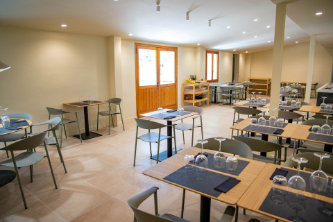 Interior de restaurante moderno en TAIGA Lake Caspe, parque vacacional en Aragón, España, con mesas puestas.