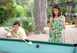 Zwei Kinder spielen im Sommer Billard im Freien im Ferienpark TAIGA Lake Caspe in Aragón, Spanien.