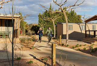 Due persone vanno in bicicletta nel villaggio turistico TAIGA Lake Caspe in Aragona, Spagna, tra le cabine.