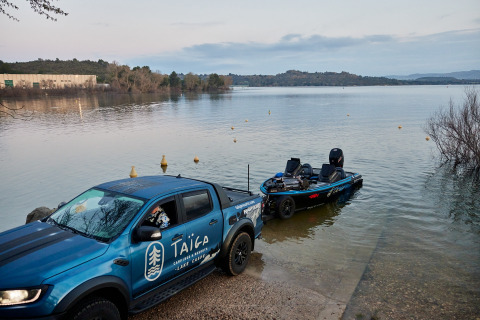 Camion blu Taiga Lake Caspe mette in acqua una barca al lago nel parco vacanze in Aragona, Spagna, immerso nella natura.