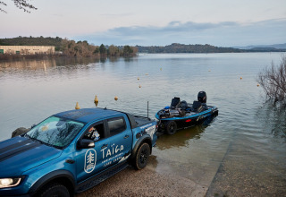Camion blu Taiga Lake Caspe mette in acqua una barca al lago nel parco vacanze in Aragona, Spagna, immerso nella natura.
