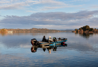 Due persone navigano su una barca da pesca nelle tranquille acque di TAIGA Lake Caspe ad Aragón, Spagna.