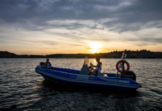 Due persone su un gommone al tramonto sul TAIGA Lake Caspe, circondati dal paesaggio collinare di Aragón, Spagna.