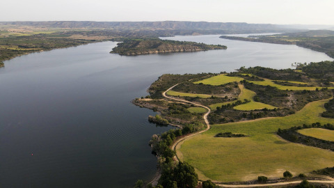 Vista aerea del parco vacanze TAIGA Lake Caspe in Aragona, Spagna, con lago, sentieri e campi verdi.