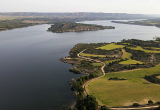 Vista aerea del parco vacanze TAIGA Lake Caspe in Aragona, Spagna, con lago, sentieri e campi verdi.