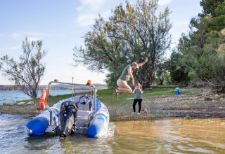 Uomo salta dalla barca alla riva al TAIGA Lake Caspe in Aragona, Spagna, donna e cane osservano.