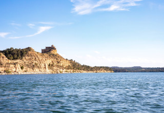 Vista su TAIGA Lake Caspe in Aragona, Spagna, con un castello in cima a una collina sotto il cielo azzurro.