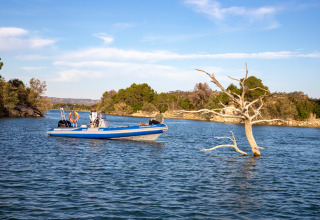 Una barca sul lago del villaggio turistico TAIGA Lake Caspe in Aragona, Spagna, accanto a un albero.