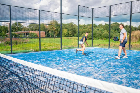 Twee mensen spelen padel op een blauw veld bij The Easy Accessible Leaf by YourNature in België.