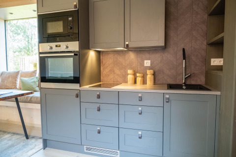 Angolo cottura blu moderno con forno, microonde e lavello al Blue Lodge by YourNature in Belgio.