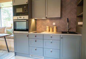Angolo cottura blu moderno con forno, microonde e lavello al Blue Lodge by YourNature in Belgio.
