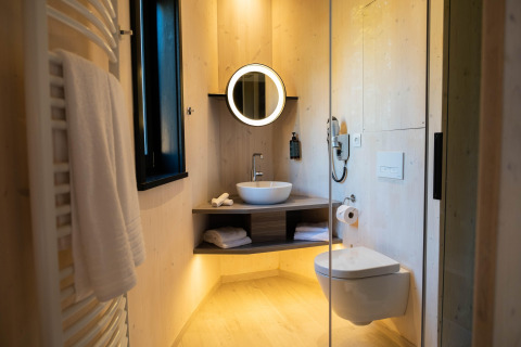 Bagno moderno in The Blue Lodge by YourNature, Belgio, con specchio circolare e WC sospeso.