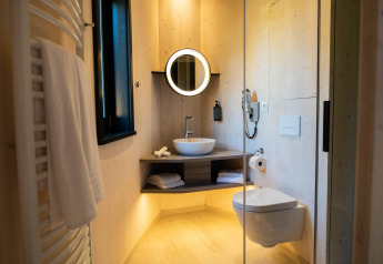 Bagno moderno in The Blue Lodge by YourNature, Belgio, con specchio circolare e WC sospeso.