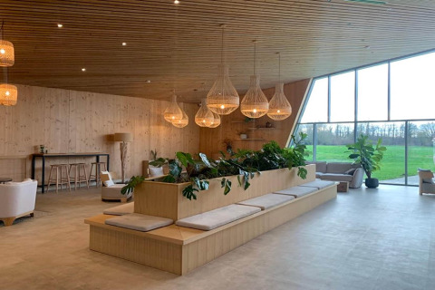 Zona lounge moderna al Blue Lodge by YourNature in Belgio, con legno, piante e ampie finestre luminose.