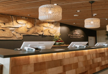 Reception di YourNature Eco Resort Belgio con decorazioni in legno, lampade a sospensione e moderni banconi.