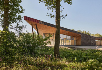 Tiny house moderna chiamata The Blue Lodge by YourNature in Belgio, immersa tra alberi e vegetazione.