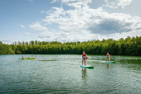 Persone fanno paddleboard e kayak su un lago circondato da foresta presso The Blue Lodge a YourNature.