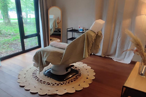 Accogliente sala trattamenti a The Blue Lodge by YourNature, Belgio, con ampia poltrona e vista sul bosco.