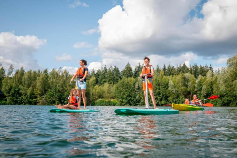 Famiglia si diverte con sport acquatici davanti a The Blue Lodge by YourNature immersa nella natura in Belgio.
