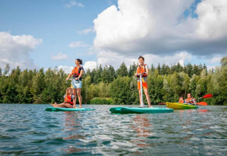 Famiglia si diverte con sport acquatici davanti a The Blue Lodge by YourNature immersa nella natura in Belgio.