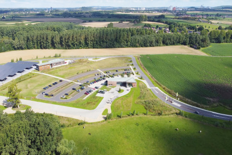 Luftaufnahme eines Tiny House mit Parkplatz, grünen Feldern und Wäldern in ländlicher Umgebung.