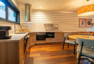 Moderne glampingkeuken in The Cottage by YourNature met houten meubels, eettafel en sfeerverlichting.