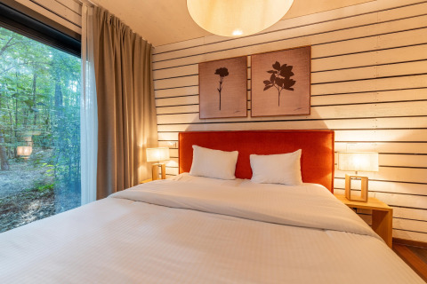 Gemütliches Schlafzimmer in The Cottage bei YourNature, großes Bett, Fenster mit Blick auf den Wald.