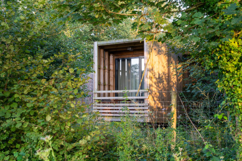 The Cottage glamping accommodatie van YourNature, een houten huisje verscholen in zomerse natuur.