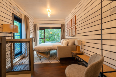 Moderne glamping slaapkamer in The Cottage by YourNature met stijlvolle inrichting en uitzicht op bos.