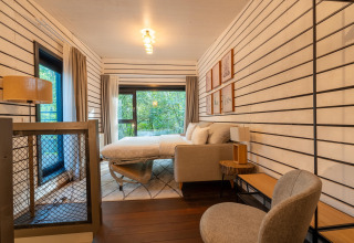 Moderne glamping slaapkamer in The Cottage by YourNature met stijlvolle inrichting en uitzicht op bos.