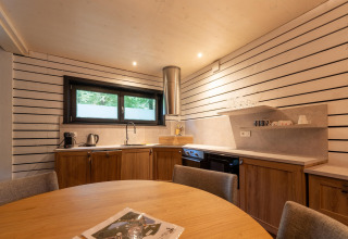 Moderne Glamping-Küche in The Cottage by YourNature mit Holzmöbeln und gemütlichem Essbereich.