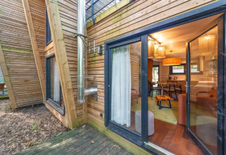 Houten glamping-accommodatie met grote ramen en buitenterras bij The Cottage van YourNature.