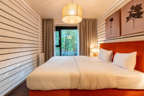 Alojamiento glamping The Cottage by YourNature con cama grande, decoración moderna y vistas al bosque.