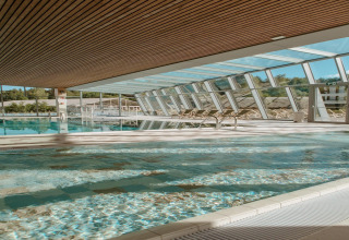 Indendørs swimmingpool med glasvægge og træloft på The Large Leaf by YourNature-lodge i Belgien.