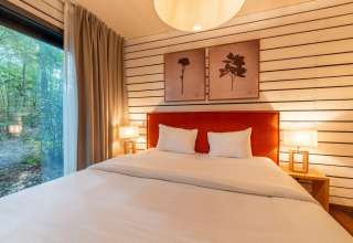 Schlafzimmer im The Cottage by YourNature in Belgien mit großem Bett, Waldblick und moderner Einrichtung.